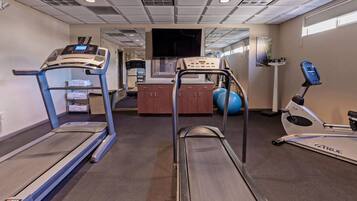 Une salle de sport équipée de tapis de course, d’un vélo d’appartement et de ballons d’exercice.