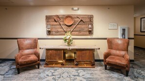 Una stanza con decorazioni murali in legno rustico, un tavolo centrale con un vaso di fiori e due poltrone in pelle.