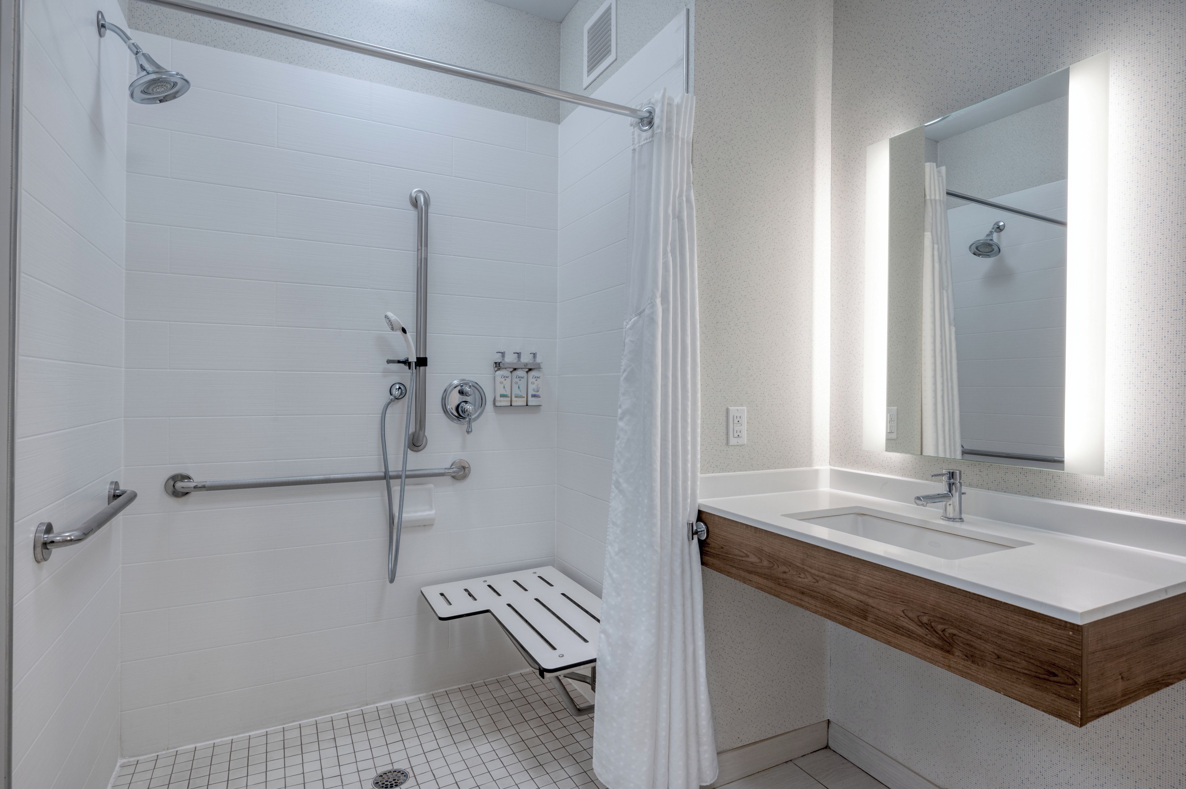 A modern bathroom with a shower, a vanity with a mirror, and a toilet.