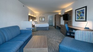 A hotel room with a bed, a sofa, a desk, and a TV. - Holiday Inn Express Radcliff-Fort Knox by IHG (Radcliff)