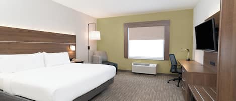 A hotel room with a bed, a desk, a chair, a television, and a window.