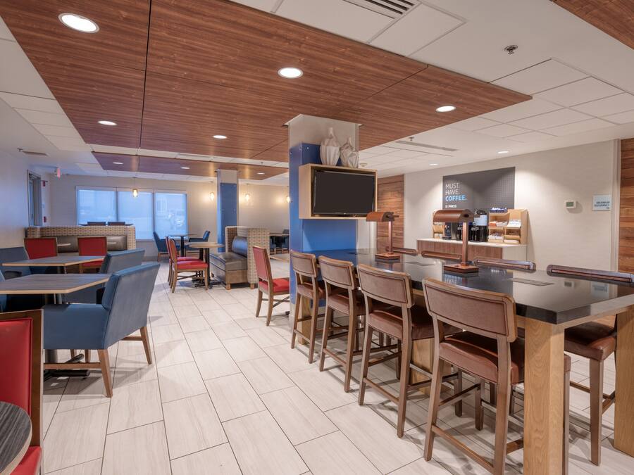 A modern cafe with wooden ceiling panels, a bar area, and seating arrangements.
