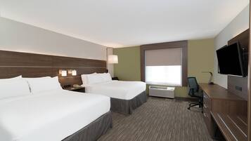 A hotel room with two beds, a desk, a television, and a window with blinds.