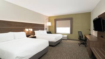 Une chambre d’hôtel avec deux lits, un bureau, une chaise, une télévision et une fenêtre avec des stores.