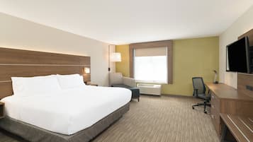 Quarto de hotel com uma cama grande, uma escrivaninha, uma cadeira, uma televisão e uma janela.