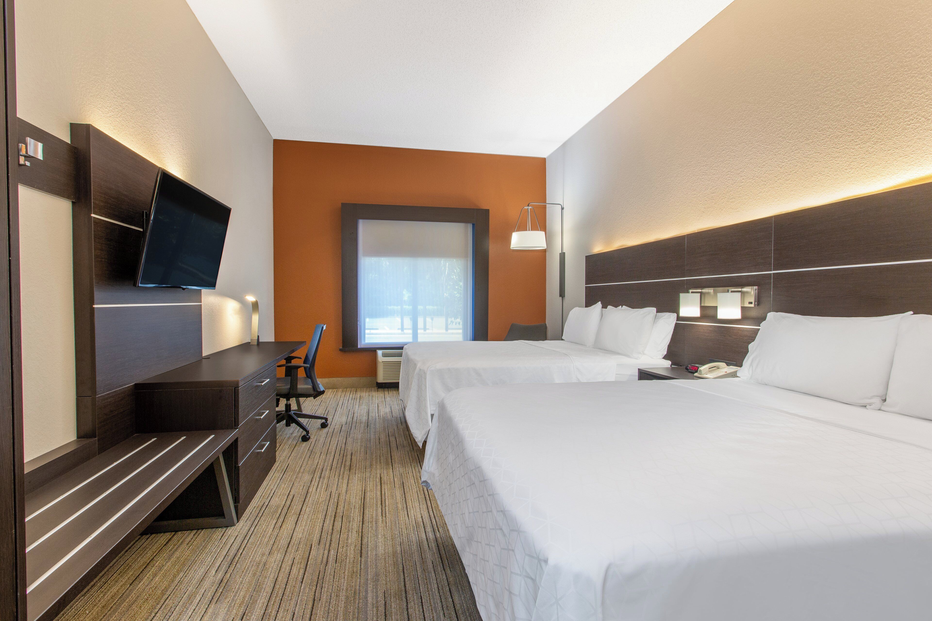 Une chambre d’hôtel avec un lit, un bureau, une chaise, une télévision et une fenêtre.