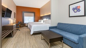 A hotel room with a bed, a blue sofa, a desk, and a TV. - Holiday Inn Express Hotel & Suites Silver Springs - Ocala by IHG (Silver Springs)