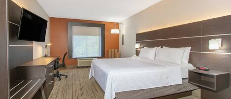 A hotel room with a bed, desk, chair, TV, and a window.
