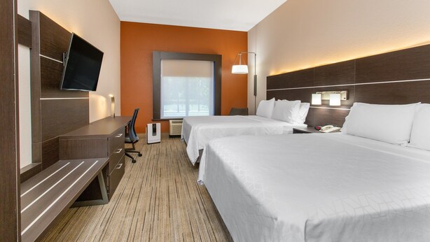 A hotel room with two beds, a desk, a flat-screen TV, a desk lamp, and a window with blinds. - Holiday Inn Express Hotel & Suites Silver Springs - Ocala by IHG (Silver Springs)
