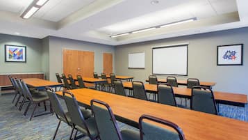 Une salle de conférence avec une longue table, des chaises, un tableau blanc et des œuvres d’art encadrées accrochées aux murs.