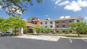 A hotel with a parking lot, trees, and a clear sky. - Holiday Inn Express Hotel & Suites Silver Springs - Ocala by IHG (Silver Springs)