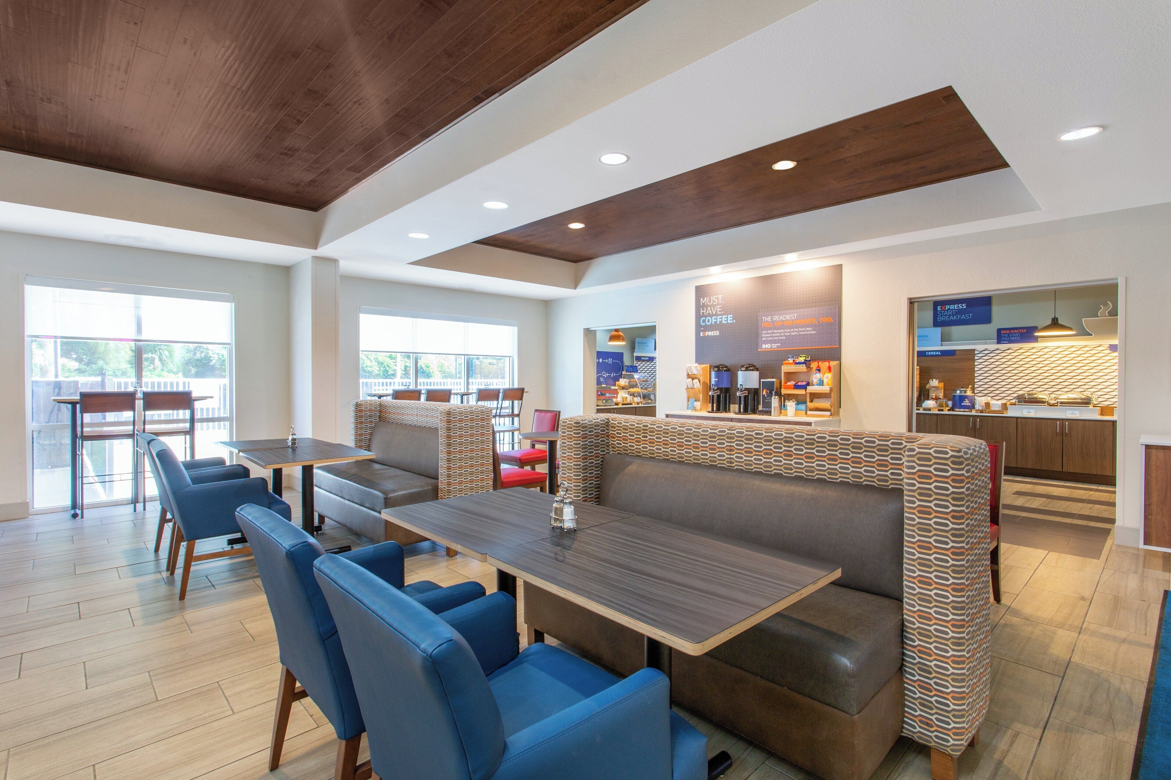 A modern restaurant with a high ceiling, wooden beams, and a mix of seating options including booths and tables.