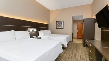 A hotel room with two beds, a desk, a television, and a framed picture on the wall.