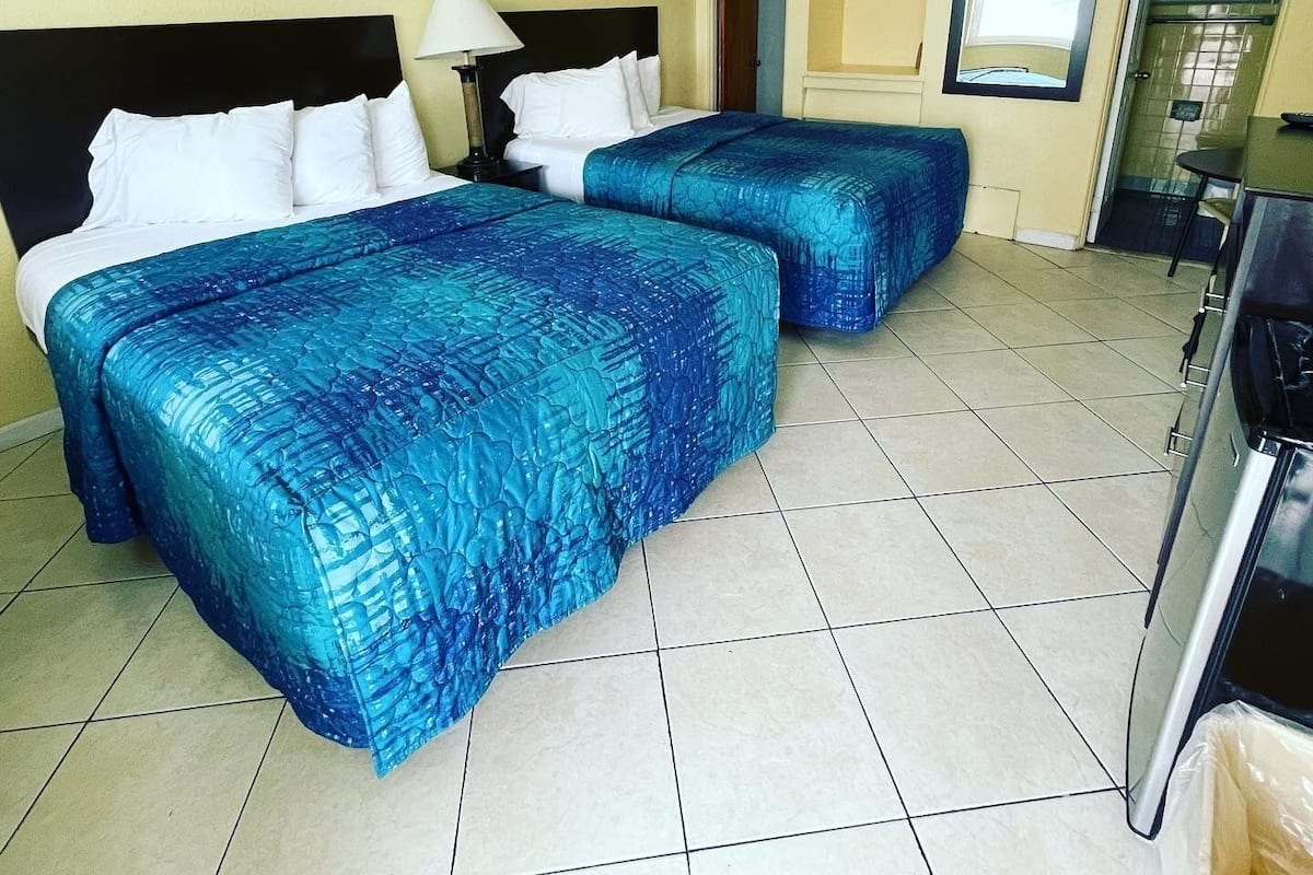 Ein Hotelzimmer mit zwei Betten, einem Schreibtisch und einer Küchenzeile.