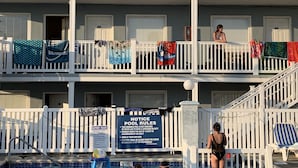 A multi-story building with balconies, a swimming pool, and a notice board with pool rules. - Sandy Shores Resort Motel (North Wildwood)
