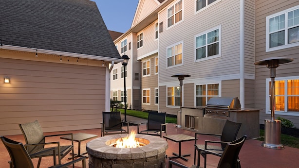 An outdoor patio with a stone fire pit, seating, and a grill area. - Residence Inn by Marriott Mt. Laurel at Bishop's Gate (Mount Laurel)