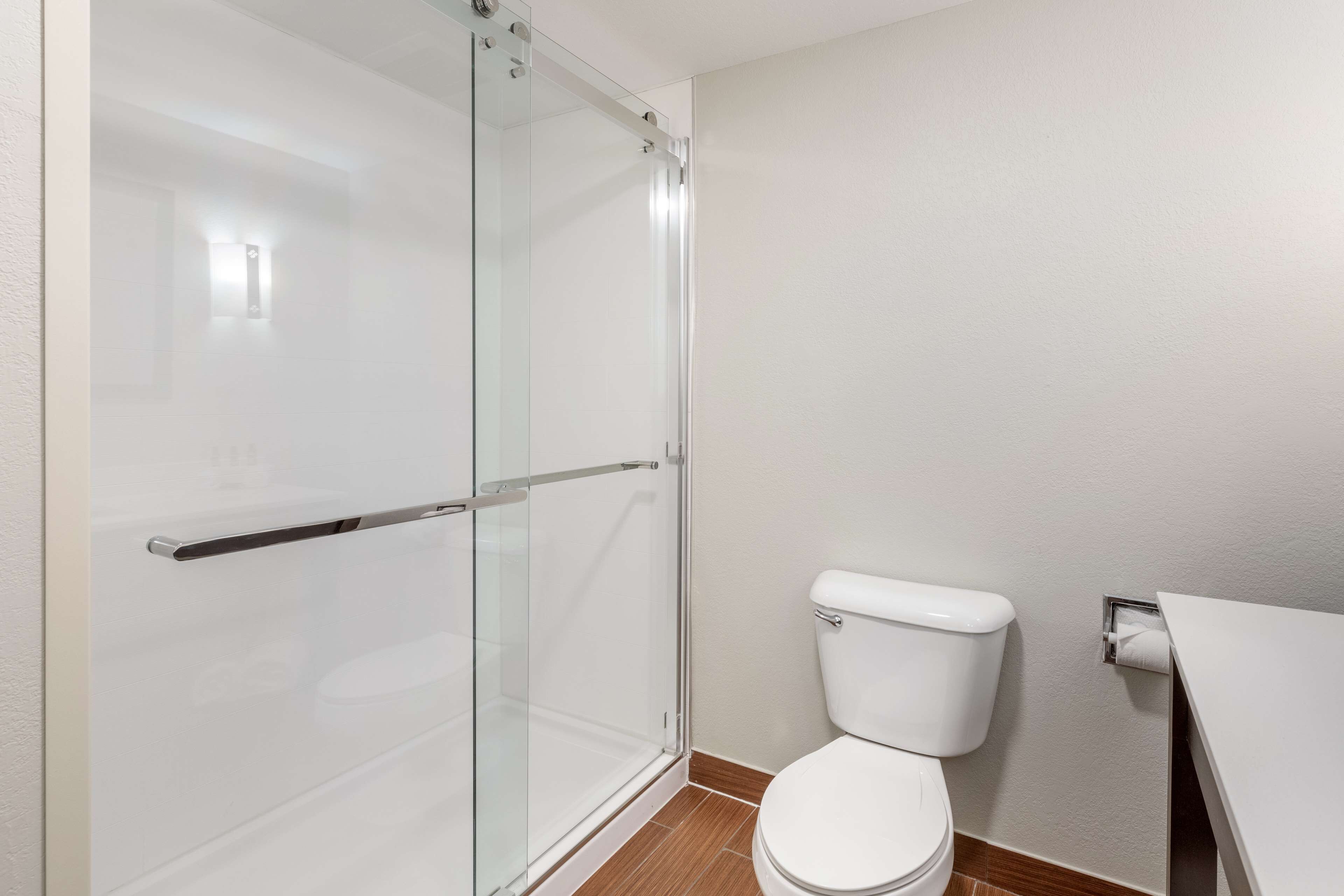 A bathroom with a glass shower enclosure, a white toilet, and a white sink.