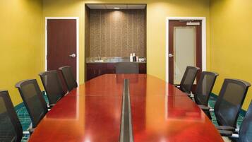 A conference room with a long table, chairs, a sink, and a patterned wall.
