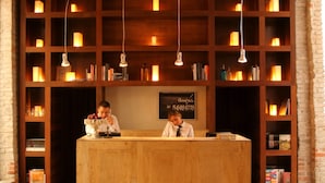 A reception desk with a wooden counter, surrounded by bookshelves and hanging light fixtures. - La Purificadora, Puebla, a Member of Design Hotels (Puebla)
