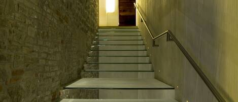 A staircase with glass steps and metal railings, leading to a door at the top.