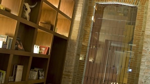 A cozy reading area with a wooden bookshelf, a table with a candle, and a brick wall. - La Purificadora, Puebla, a Member of Design Hotels (Puebla)