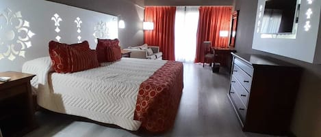 A bedroom with a bed, a dresser, a desk, and a mirror.