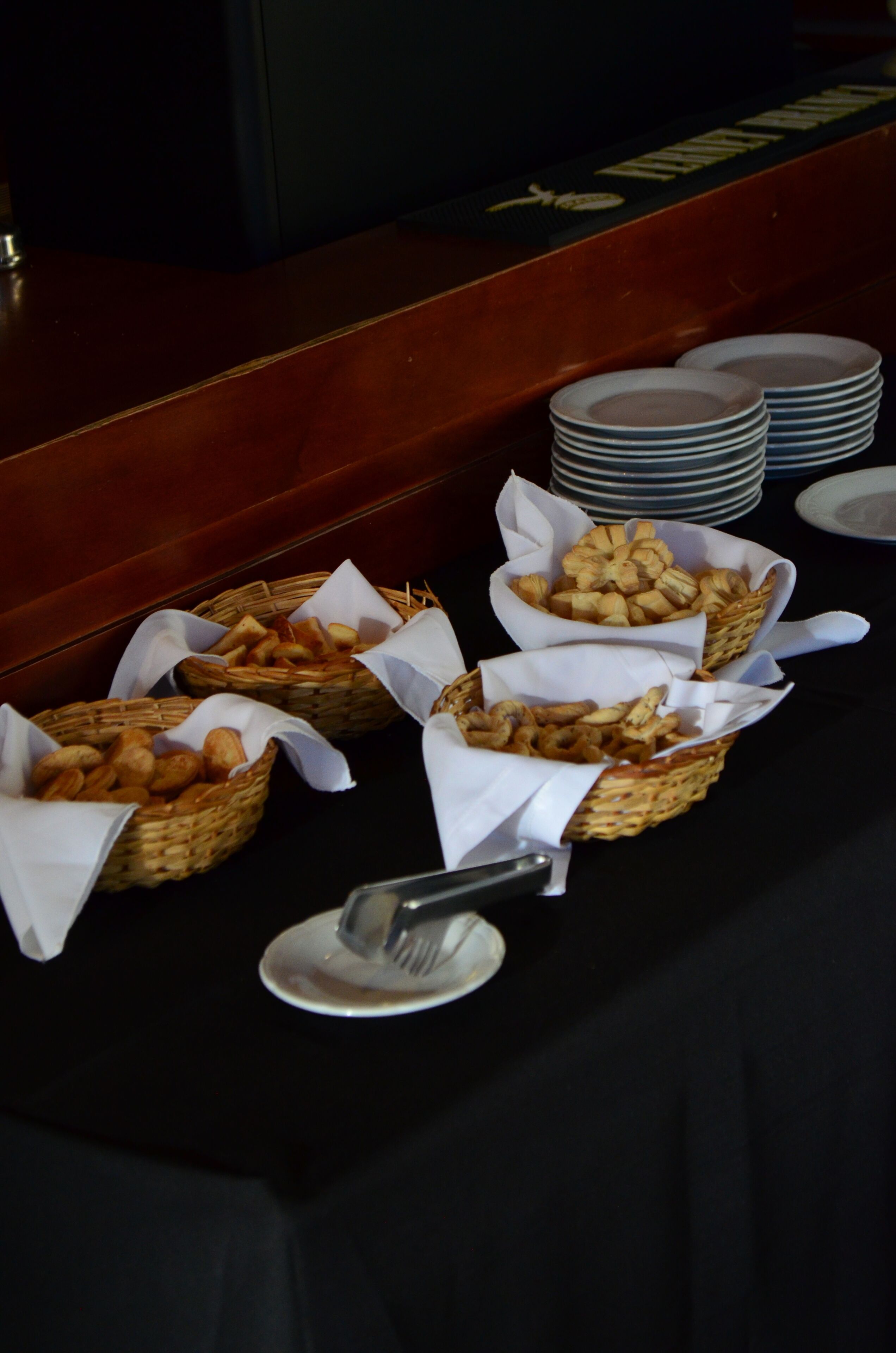 Una mesa de buffet con cestas de comida y platos apilados.
