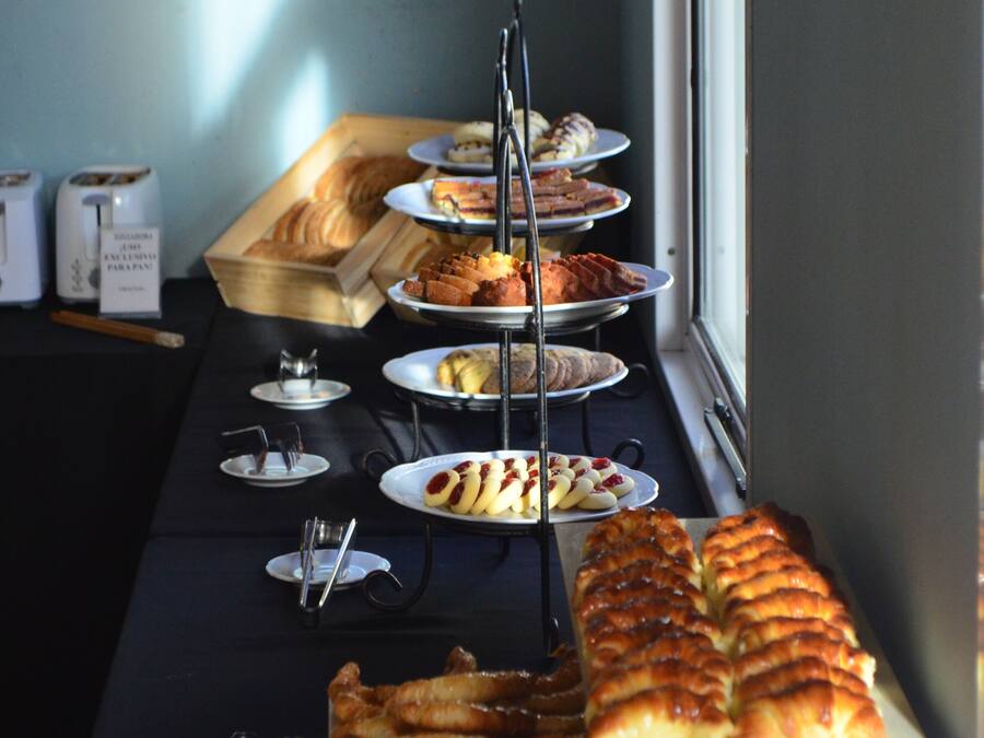 Ein reichhaltiges Buffet mit verschiedenen Backwaren und Brot, angerichtet auf einem Tisch in der Nähe eines Fensters.