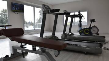 Un gimnasio con una banca, cintas de correr y una bicicleta estática.
