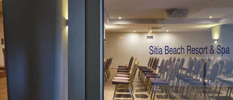 A room with rows of chairs and a sign reading "Sitia Beach Resort & Spa".