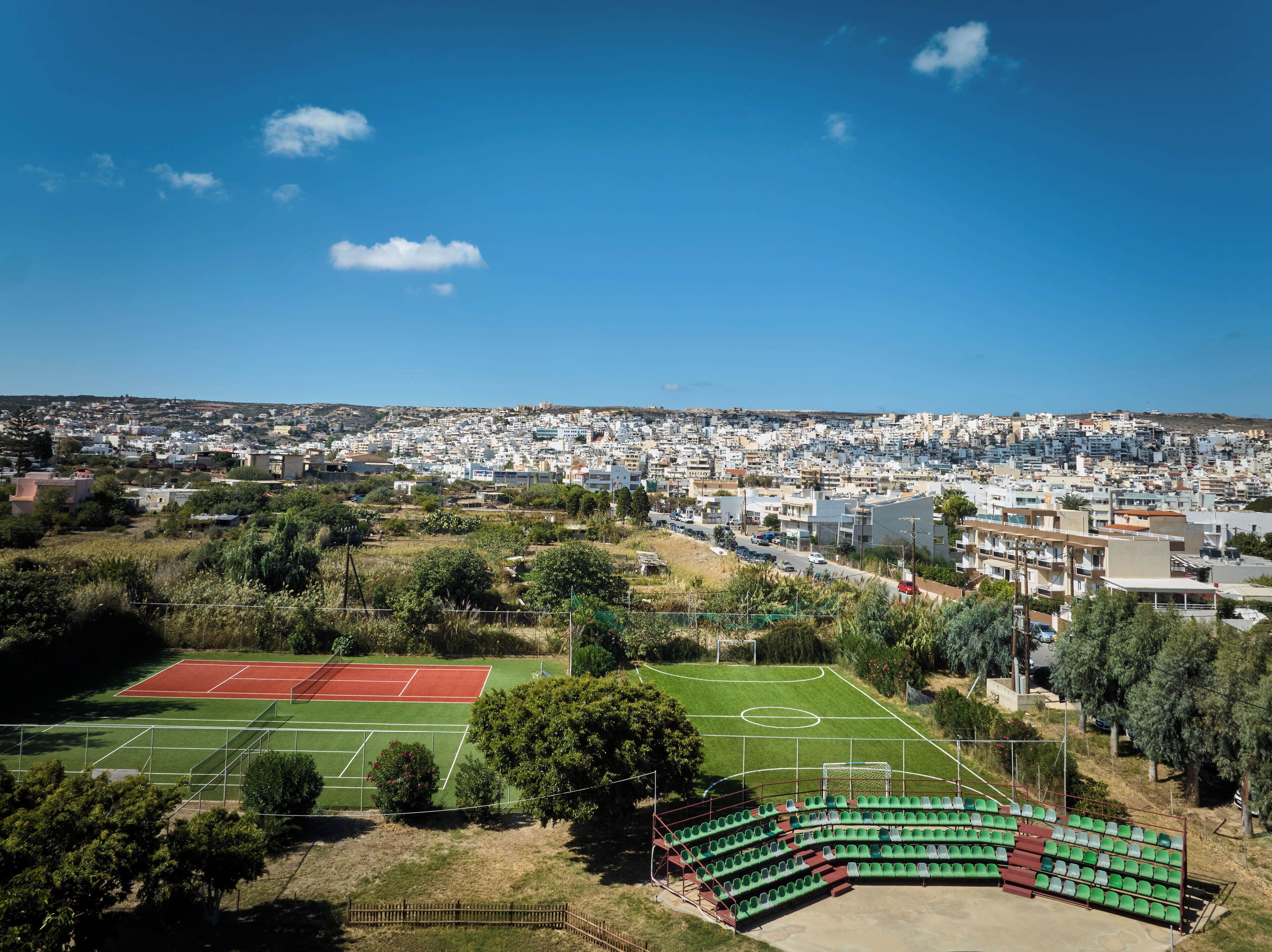 A view of a residential area with a sports field and stadium seating.