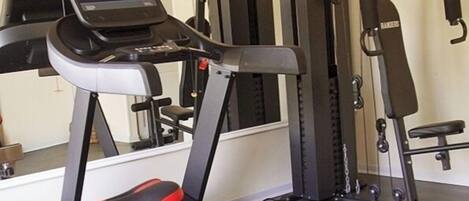 Un gimnasio con cintas de correr, máquinas de pesas y un banco.
