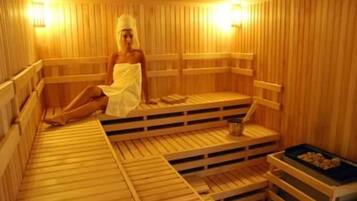 A sauna with wooden benches and a person sitting on one.