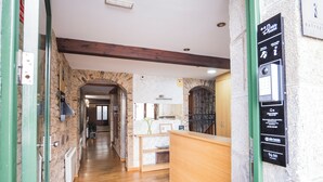 Un vestíbulo de hotel con paredes de piedra, suelos de madera, un mostrador de recepción y una señalización con información del hotel.