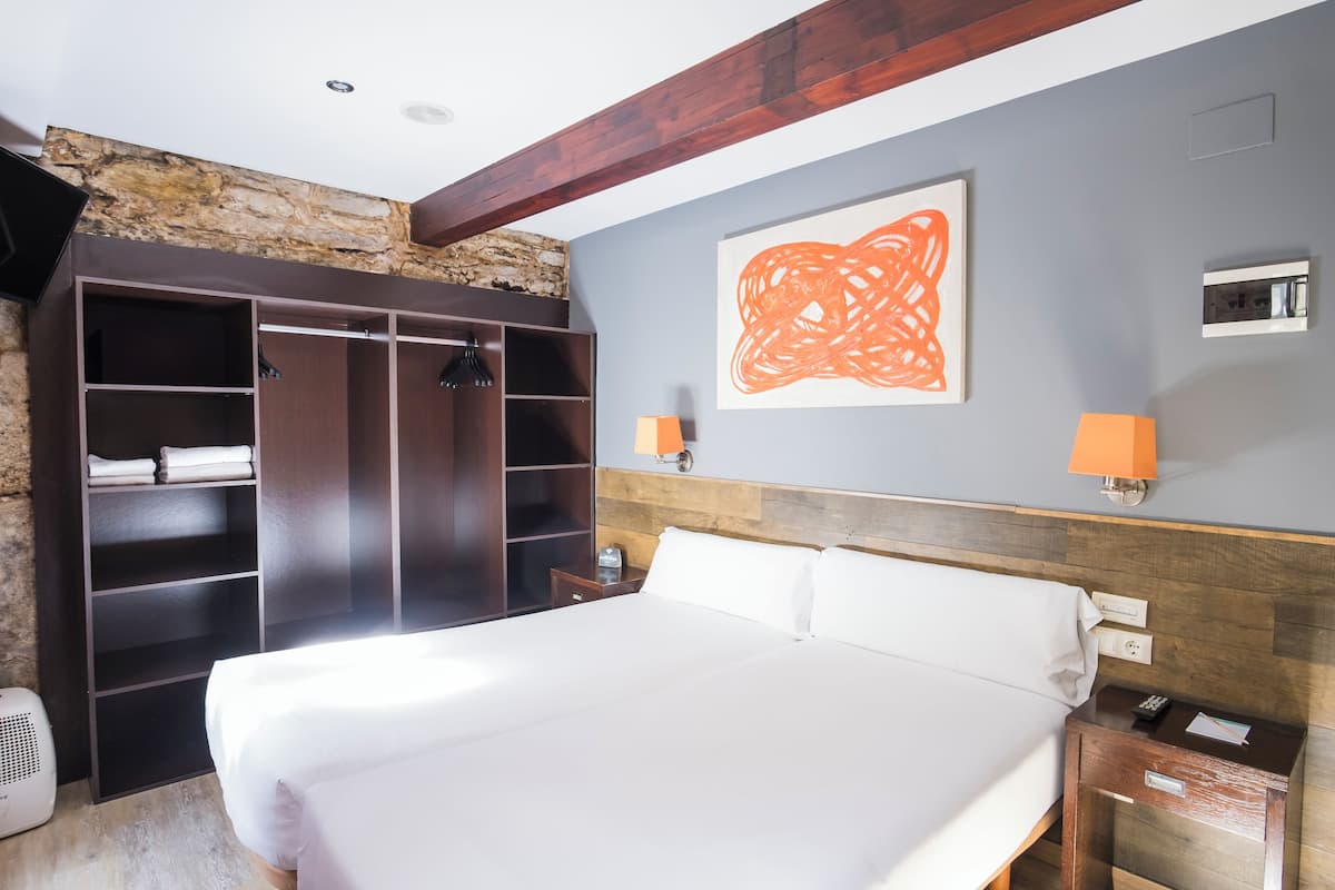 Habitació d'hotel amb un llit gran, un armari, una paret decorada amb pedra i un quadre abstracte modern.