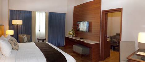Una habitación de hotel con cama, escritorio, televisor y zona de estar.