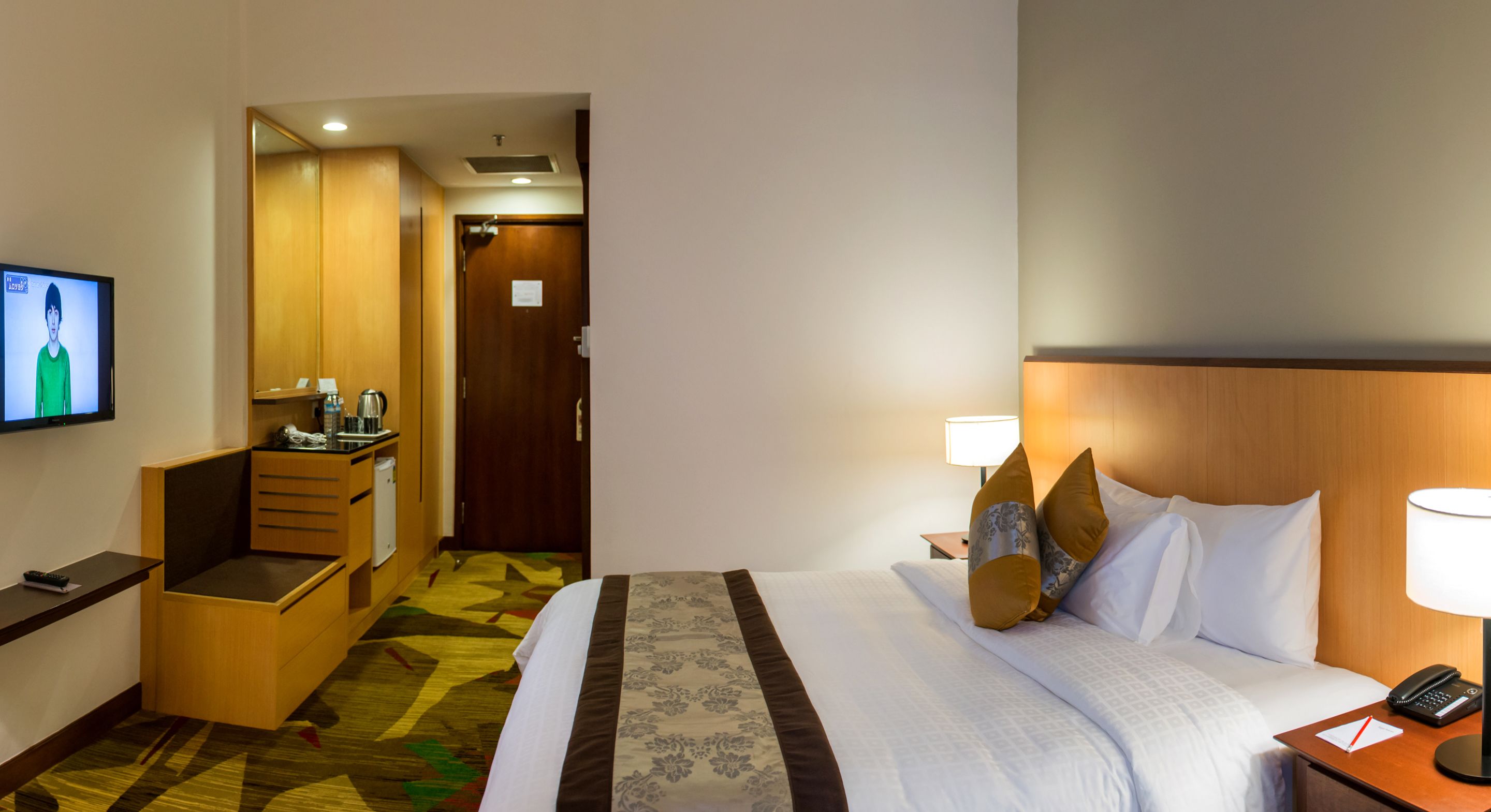 Une chambre d’hôtel avec un lit, un bureau, une télévision et une salle de bain, le tout visible à travers une porte ouverte.
