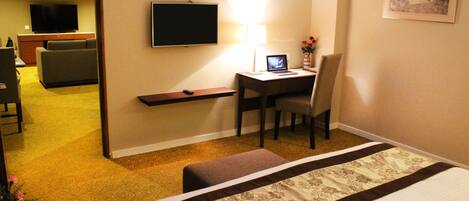 Una habitación de hotel con una cama, un escritorio con una computadora portátil, un televisor y una silla.
