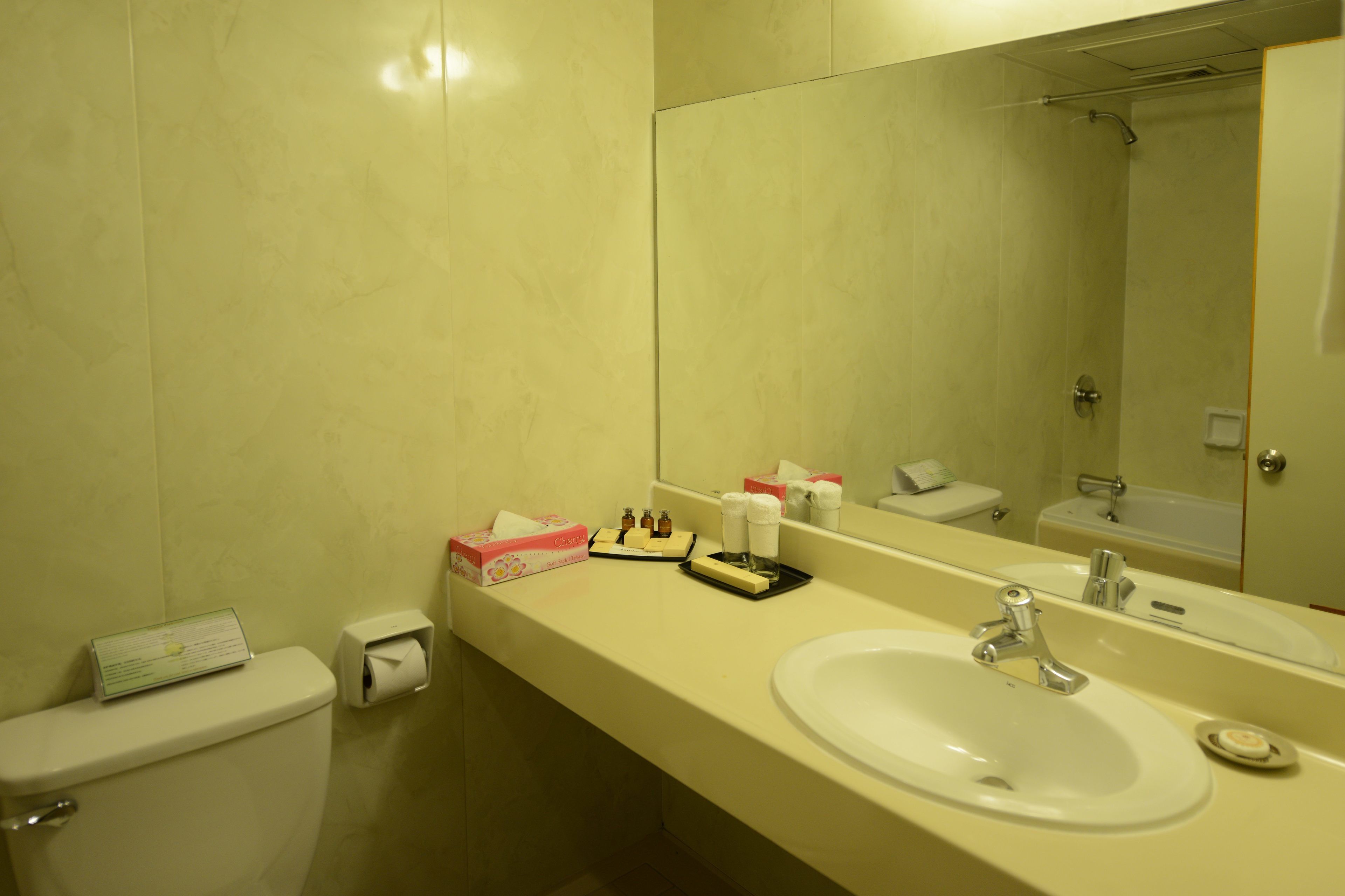 A bathroom with a toilet, sink, and mirror. There are toiletries on the counter.