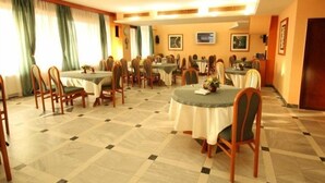 Uma área de refeições de hotel com várias mesas e cadeiras, dispostas em um espaço amplo.