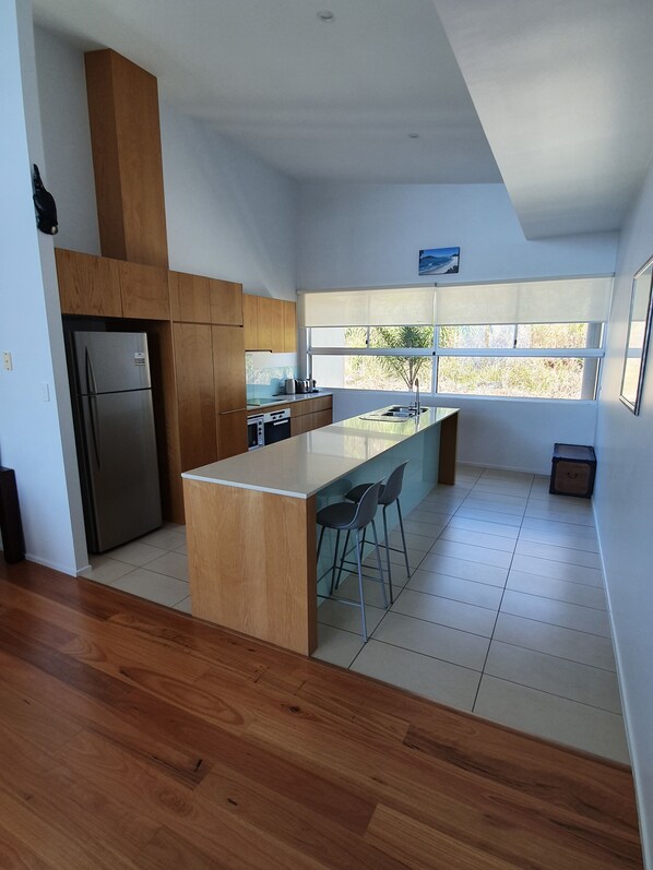 Una cocina moderna con una isla central, armarios de madera y un refrigerador de acero inoxidable.