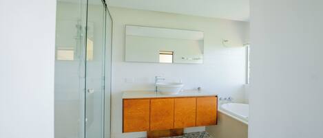 Un bagno con box doccia in vetro, mobile lavabo in legno e un water.