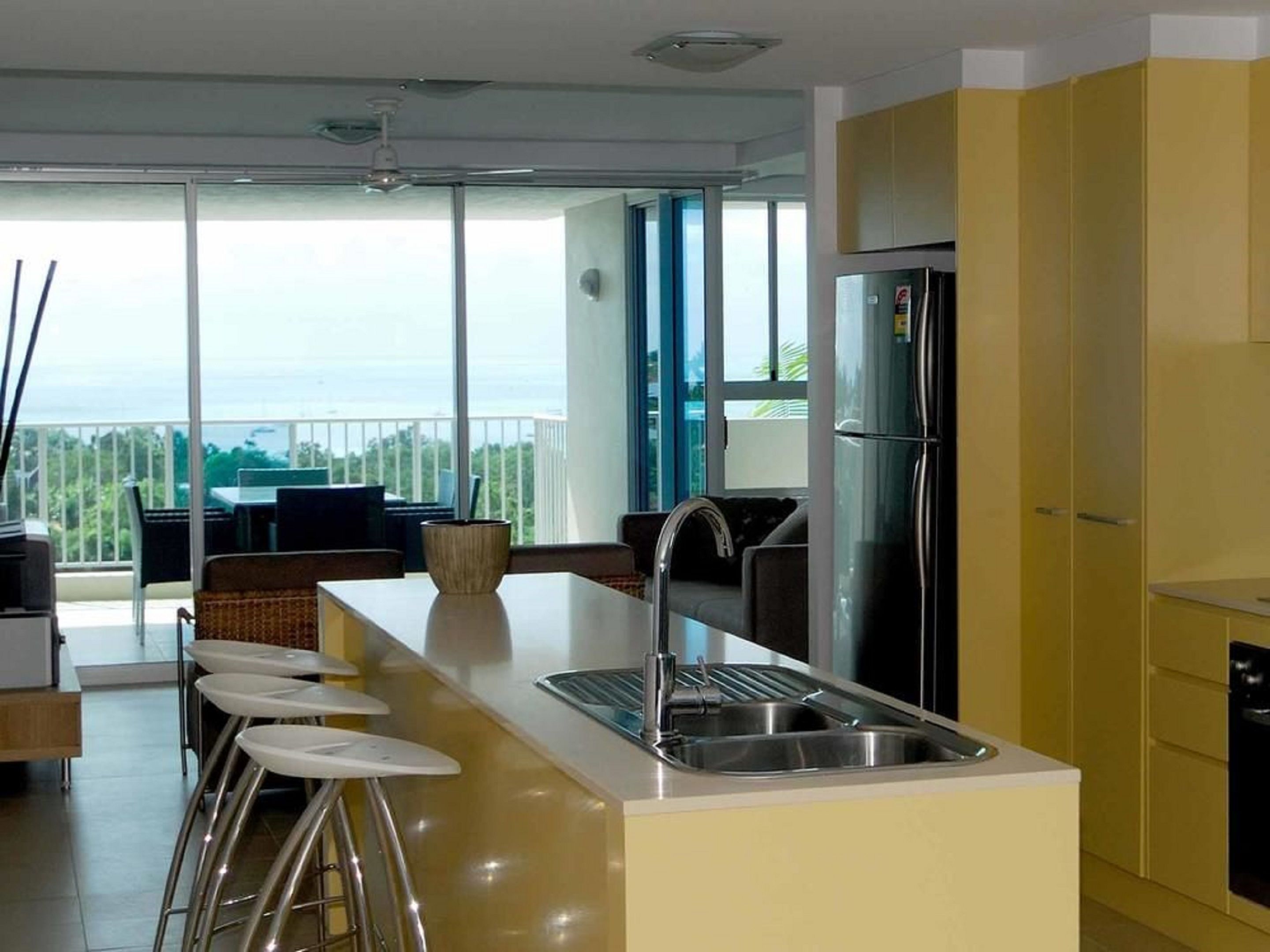 Uma cozinha moderna com uma ilha central, banquetas e vista para o exterior.