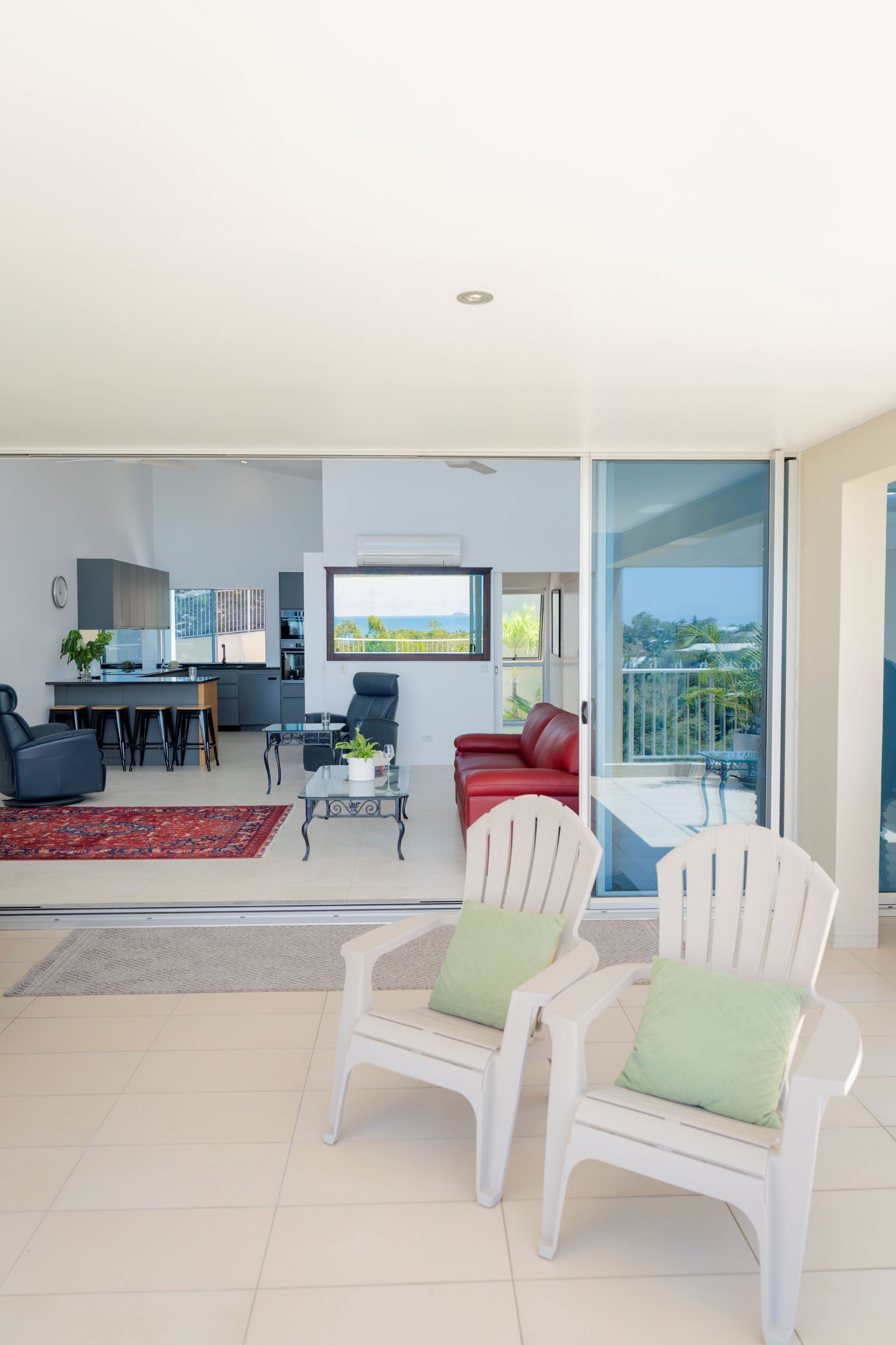 Una sala de estar moderna con comedor, un sofá rojo y un balcón con vistas.