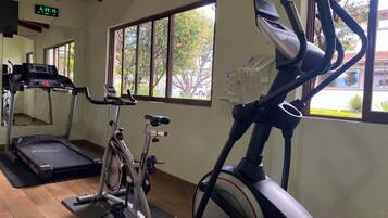 A gym with a treadmill, stationary bike, and elliptical machine.