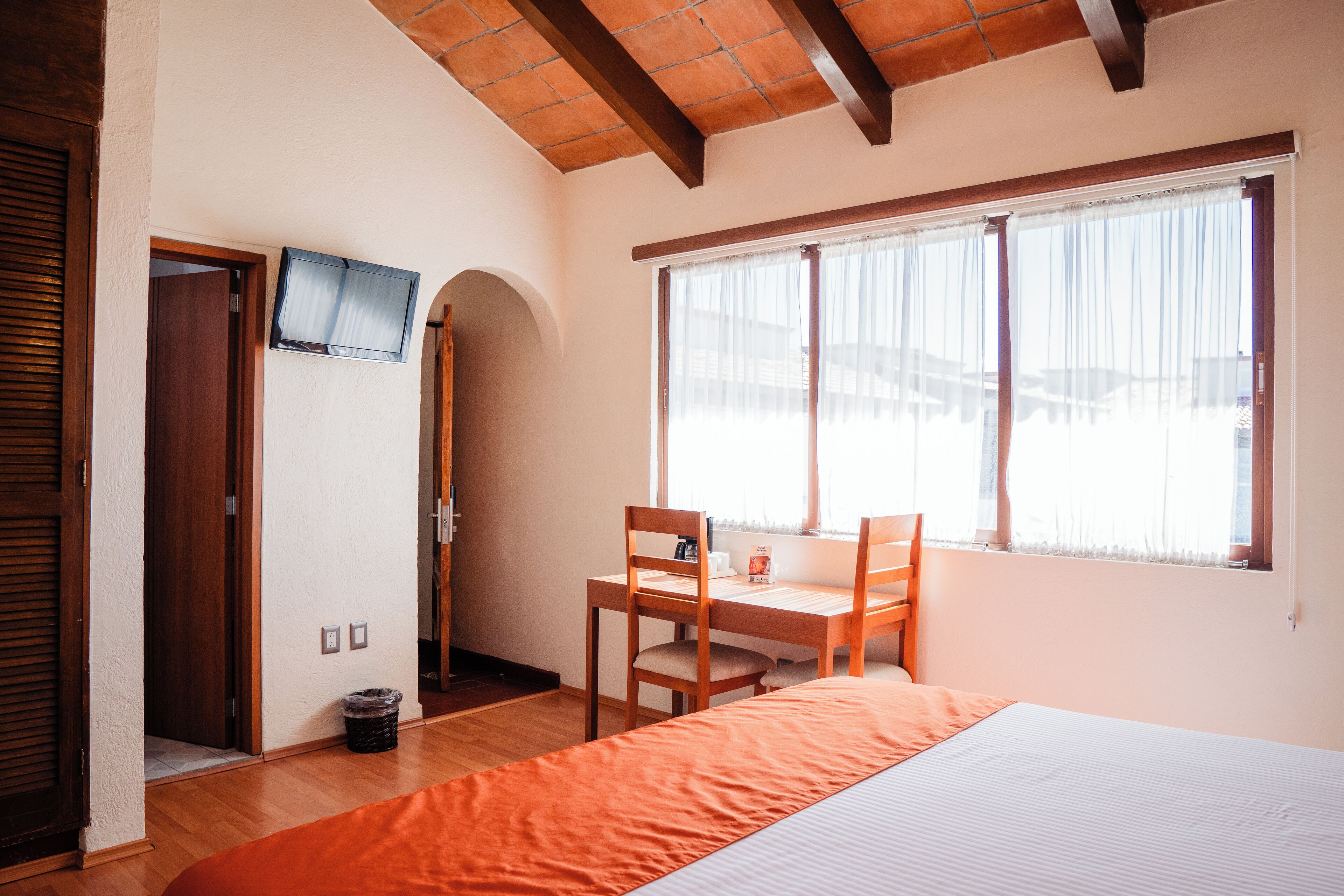 A room with a bed, a desk, and a window with curtains.