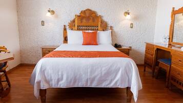 A bedroom with a large bed, wooden headboard, two bedside tables, a dresser, and a mirror.