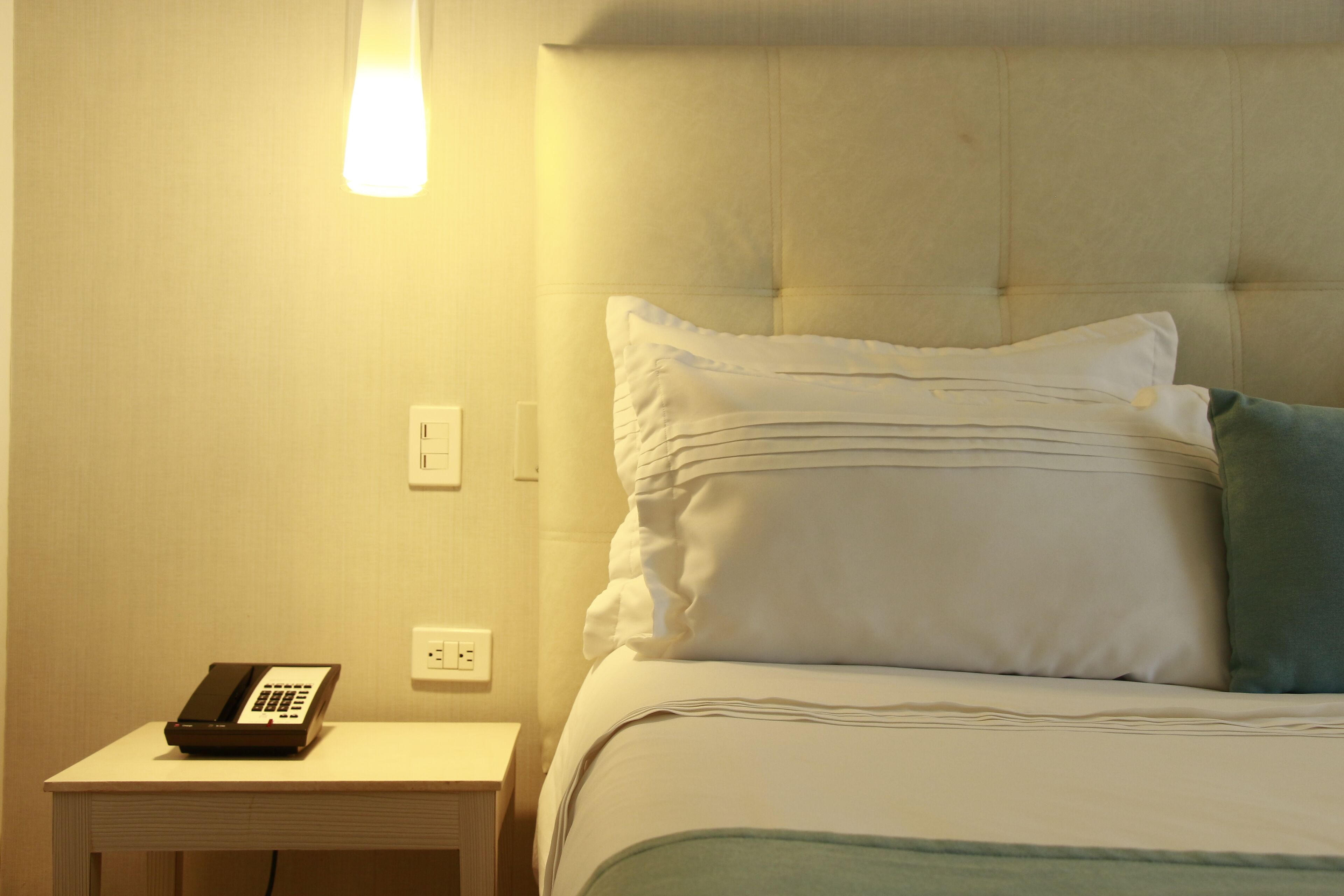 Une chambre d’hôtel avec un lit, des oreillers, une table de chevet et un téléphone.