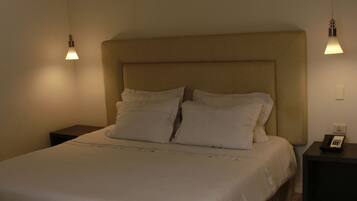 A neatly made bed with a headboard, two bedside tables, and a wall-mounted telephone.
