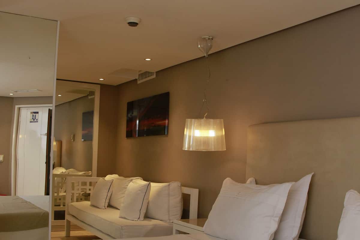 A hotel room with a large bed, a sofa, a desk, and a lamp.